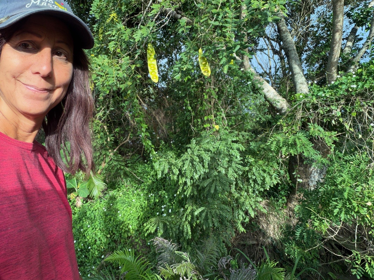 Luisa Szakacs on a village walk in Fiji, standing next to a curry leaf tree and tropical vegetation.